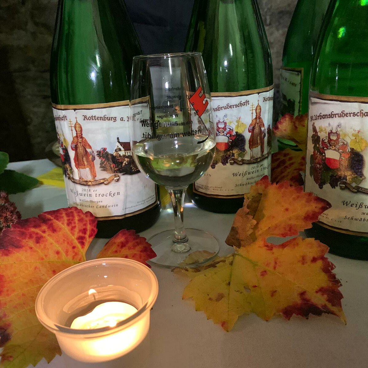 Drei Weinflaschen, ein Glas und Herbstblätter