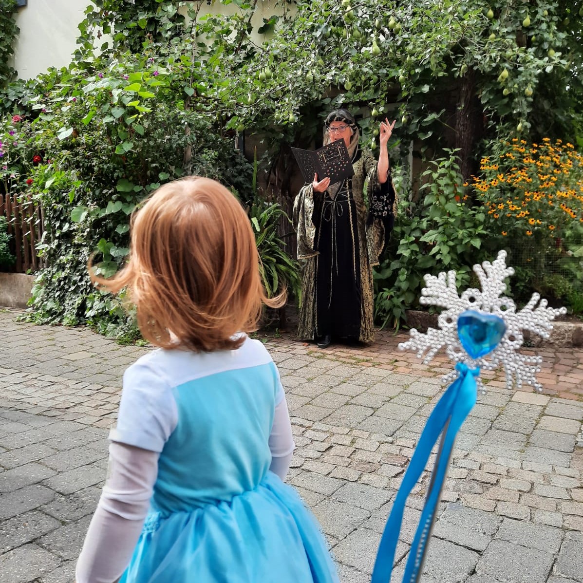 Kind im Kostüm schaut zu wie verkleidete Stadtführerin aus einem Buch vorliest