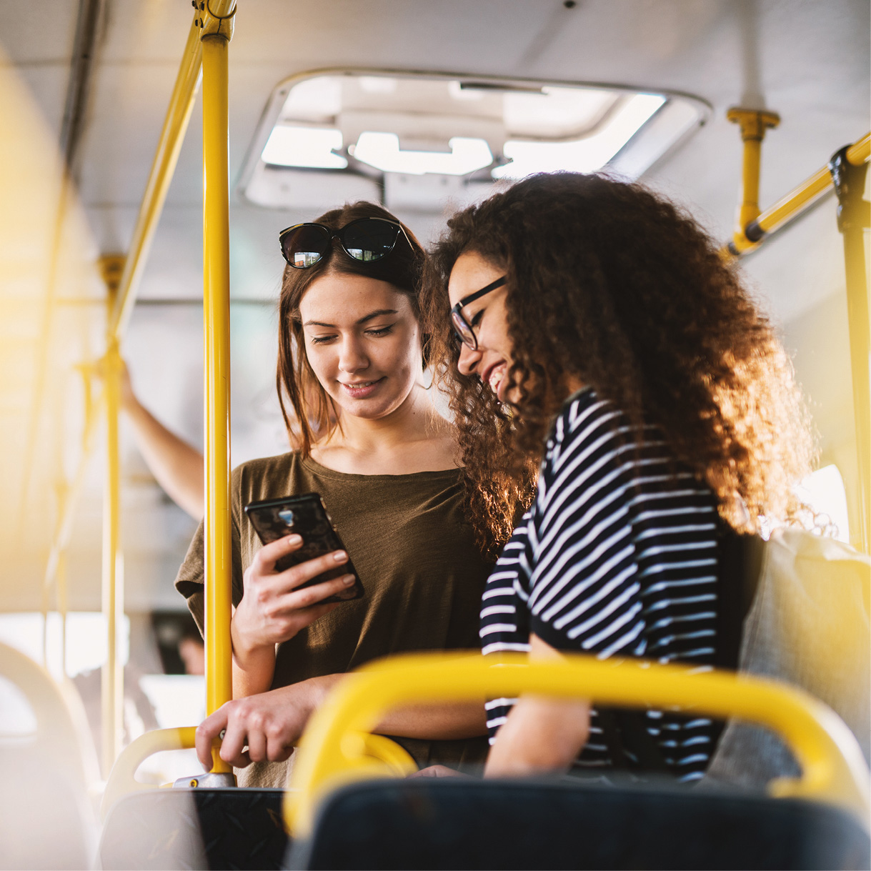 Zwei Frauen im Bus schauen auf ein Smartphone