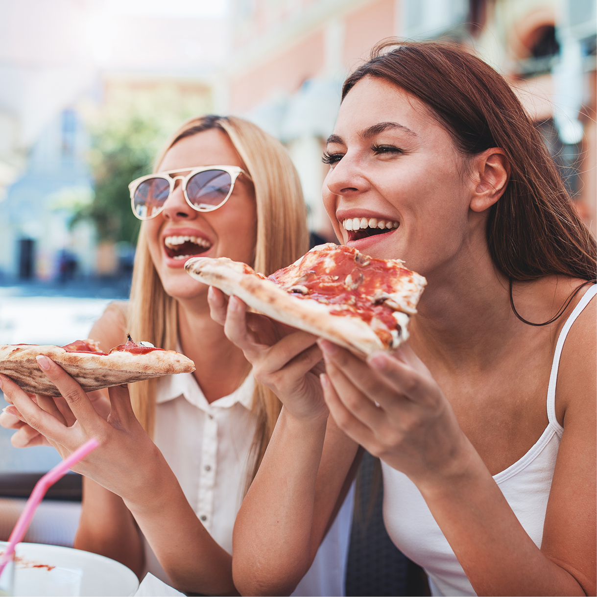 Zwei Frauen lachen und essen Pizza