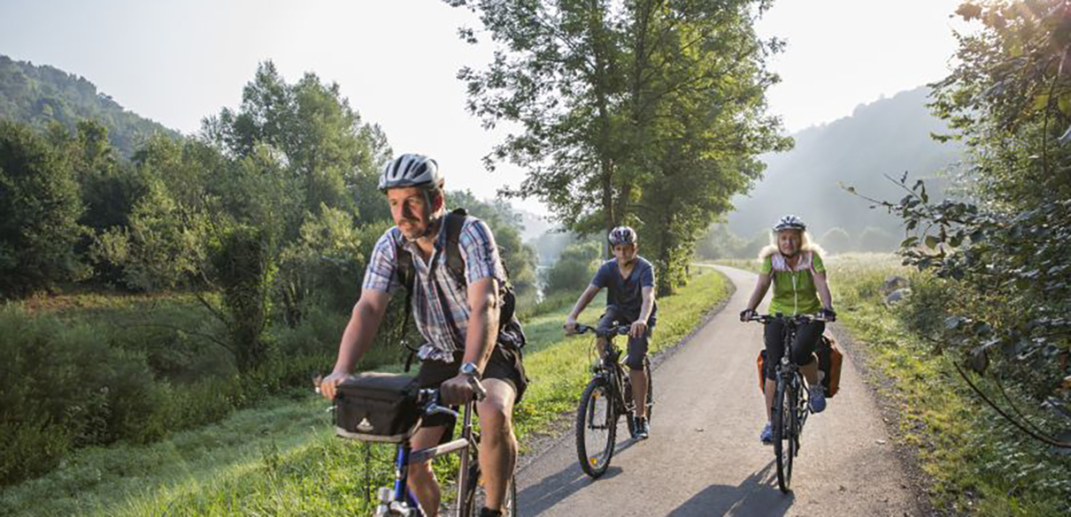 3 Fahrradfahrer fahren auf einem Radweg neben dem Neckar 